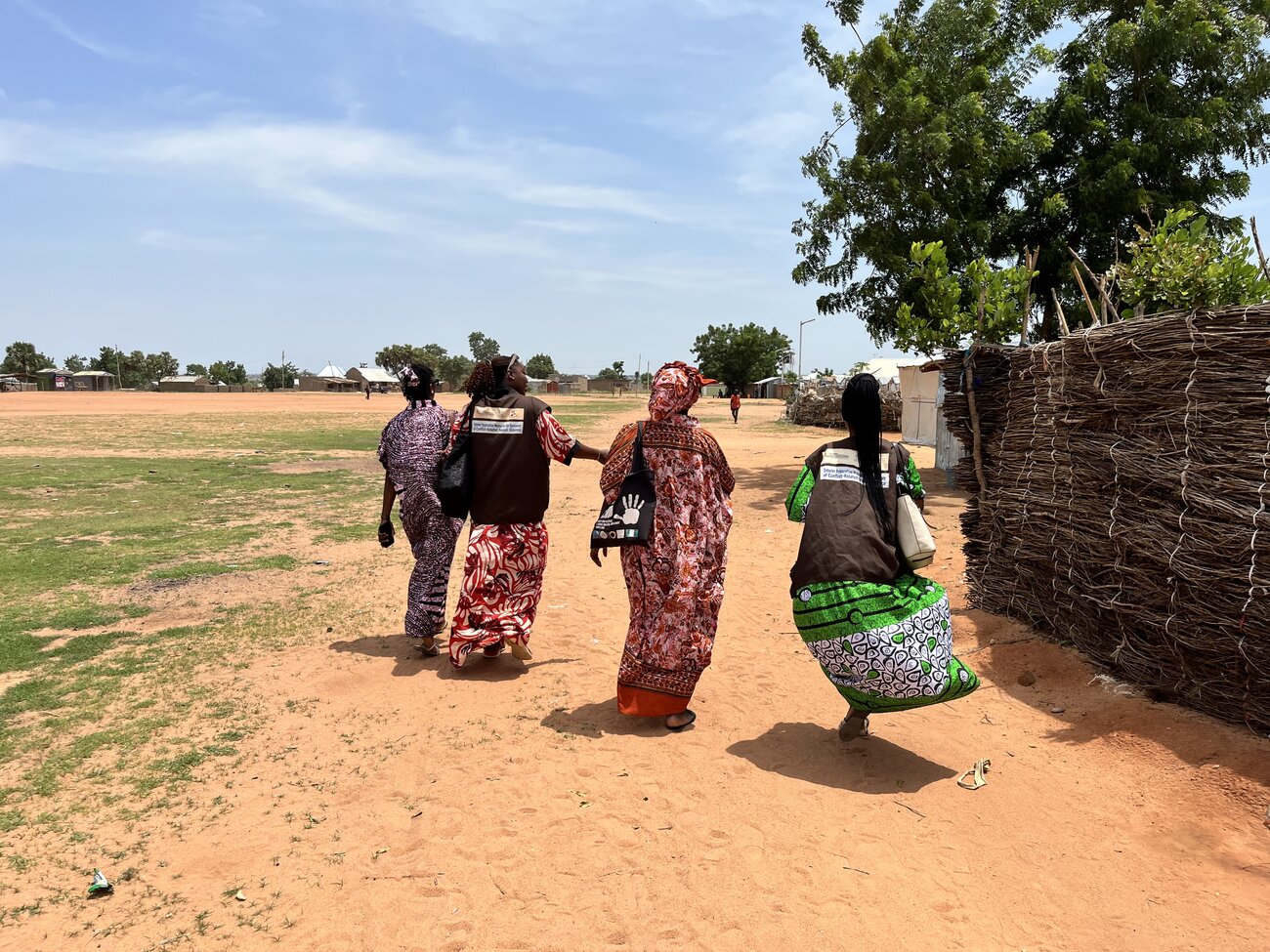 Four caseworkers walking to a survivor's house in Girei. Caseworkers hold an important role in the project as they accompany and support survivors participants throughout the project. Nigeria, June 2025. Sarah-Eve Hammond/GSF