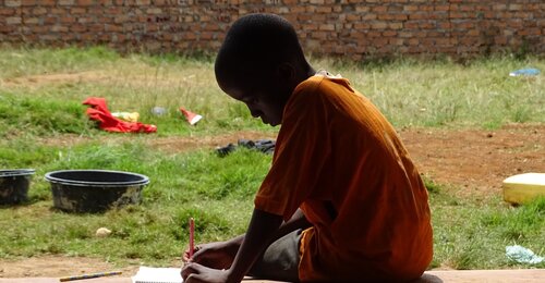 Ugandan child sitting on the floor and drawing